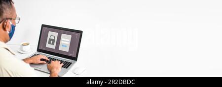 Geschäftsmann, der Daten mit einem Laptop eingibt und privat zu Hause arbeitet. Ein junger Mann mit einer Maske. Benutzer, die den Anmeldebildschirm eines Notebook-Computers verwenden. Co Stockfoto