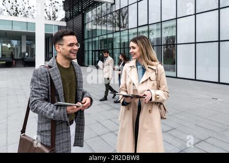 Junge Geschäftsleute Geschäftsmann und Geschäftsfrau gehen vom Bürogebäude zum Gebäude zwischen Meetings, wo sie Mitarbeiter zu besseren und besseren Schulen Stockfoto