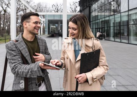 Junge Geschäftsleute Geschäftsmann und Geschäftsfrau gehen vom Bürogebäude zum Gebäude zwischen Meetings, wo sie Mitarbeiter zu besseren und besseren Schulen Stockfoto