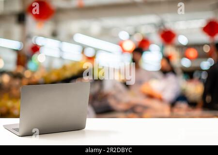 Die Rückseite des Laptops oder Notebooks ist leer und wird auf einem weißen Schreibtisch in einem Büro abgelegt. Technisches Arbeitskonzept, Smartphone, Internet, Kopierbereich r Stockfoto