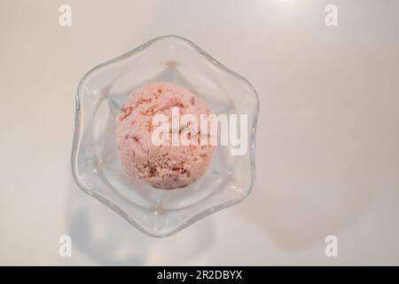 Im Sommer wird in einer Eisdiele pinkfarbenes Eis in einer Tasse auf einen weißen Tisch gestellt. Nahaufnahme, selektiver Fokus, Platz rechts für Design oder Conten kopieren Stockfoto