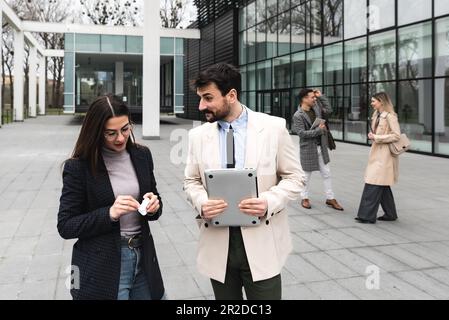 Junge Geschäftsleute Geschäftsmann und Geschäftsfrau gehen vom Bürogebäude zum Gebäude zwischen Meetings, wo sie Mitarbeiter zu besseren und besseren Schulen Stockfoto