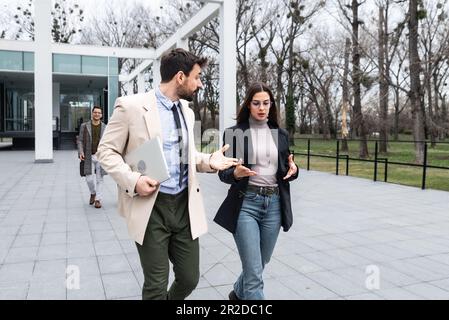 Junge Geschäftsleute Geschäftsmann und Geschäftsfrau gehen vom Bürogebäude zum Gebäude zwischen Meetings, wo sie Mitarbeiter zu besseren und besseren Schulen Stockfoto