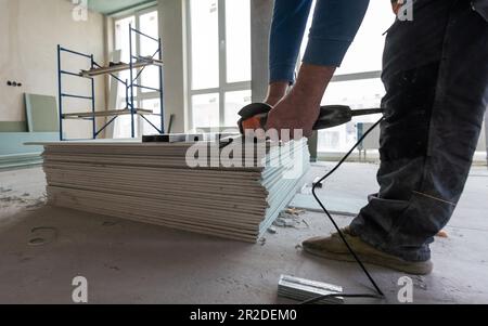 Drywall Installers. Men holding a gypsum board figured cut Stockfoto