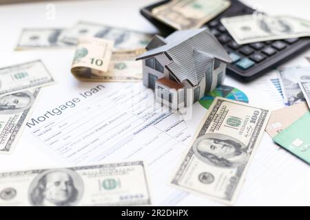 Buchhalter, der an Einkommensteuerformularen oder Budgetplanung mit Währungsnotizen, Taschenrechner und Haus-3D-Modell arbeitet Stockfoto