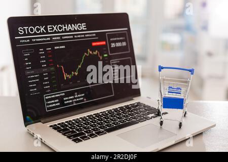 Ein Miniwagen aus einem Supermarkt steht auf einer Laptop-Tastatur. Austausch Stockfoto