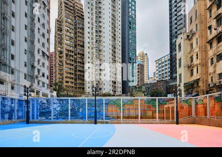 Hongkong, China - April 10 2023: Farbenfroher Basketballplatz zwischen Hochhäusern und Apartments Stockfoto