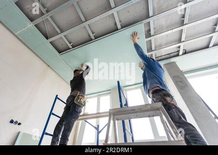 Drywall Installers. Men holding a gypsum board figured cut Stockfoto