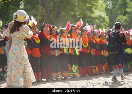 Ein Tourist, der die Kalash-Frauen beim Chilam Joshi Festival in Chitral beobachtet Stockfoto