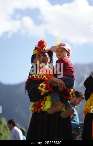 Bamburet, KPK, Pakistan - 05152023: Eine Kalash-Frau in traditionellem Kostüm, die ein Kind beim Chilam Joshi Festival in Chitral hält Stockfoto