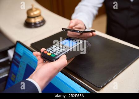 Administrator mit Kreditkartenleser, männlicher Kunde, der kontaktlose Zahlungen tätigt Stockfoto