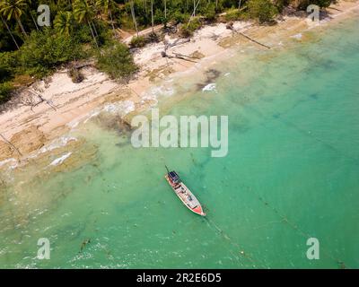 Traditionelle thailändische Langschwanz-Fischerboote vor einem kleinen, von Palmen gesäumten tropischen Strand (Khao Lak, Thailand) Stockfoto