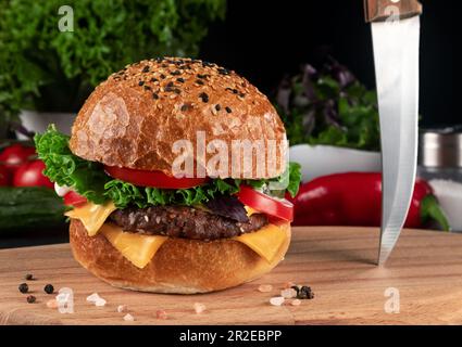 Cheeseburger: Amerikanischer Burger mit frischem Gemüse auf Holzbrett. Stockfoto