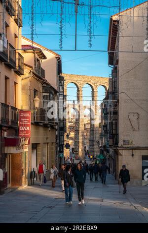 Blick auf die Plaza Azoguejo im Zentrum der Stadt. Farben des Sonnenuntergangs. Gäste, die sich in den Bars und Restaurants auf der Straße von Segovia entspannen möchten. Stockfoto