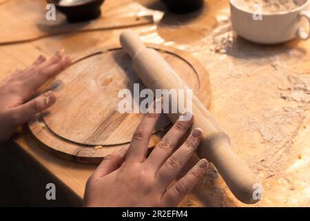 Kochhände und eine hölzerne Nadel, Backgeräte Nahaufnahme mit selektivem Weichzeichner Stockfoto