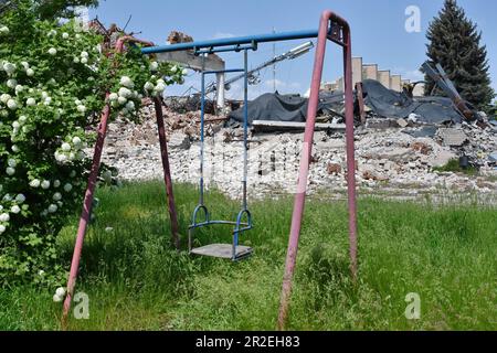 Huliaipole, Ukraine. 18. Mai 2023. Verlassene Kinderschaukel, gesehen von dem Gebäude, das durch russische Bombenangriffe zerstört wurde. Kriegskrise in Huliaipole, Ukraine Kredit: SOPA Images Limited/Alamy Live News Stockfoto