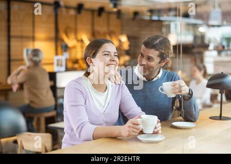 Fröhlicher Mann und Frau, die ein Date in einem gemütlichen Café genießen Stockfoto