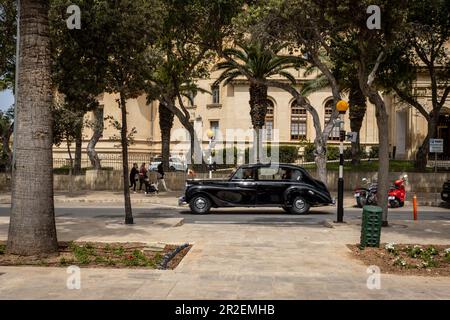 Valletta, Malta - 16. April 2023: Eine schwarze diplomatische Limousine fährt eine Straße in Floriana. Stockfoto