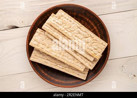 Mehrere Roggen-Knusperbrote mit einer Tonplatte auf einem Holztisch, Nahaufnahme, Draufsicht. Stockfoto