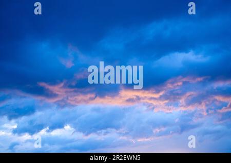 Wunderschöne dunkelblaue Wolken in Pink und Orange. Farbenfroher Himmel bei Sonnenaufgang oder Sonnenuntergang. Stockfoto