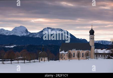 Wallfahrtskirche Wilparting am Irschenberg mit Schnee im Winter bei Sonnenaufgang, mit Bergen im Hintergrund, Bayern Stockfoto