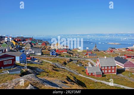 Disco-Bucht; Westgrönland; hell bemalte Holzhäuser von Ilulissat; Blick auf die Disko-Bucht; schwimmende Eisschollen; bergiges Gelände; Bergkette Stockfoto