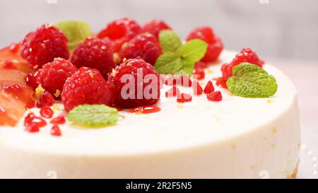 Käsekuchen mit frischen Himbeeren, Pflaumen und Minzblättern. Stockfoto