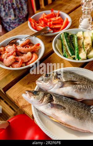 Frischer Fisch und Gemüse auf einem Holztisch Stockfoto