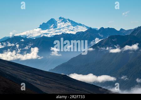 Blick auf die nahe gelegenen Berge, die von niedrigen Wolken bedeckt sind, von den Hängen des majestätischen Vulkans Osorno am Llanquihue-See, in der Nähe von Puerto Montt, Los Lagos, Stockfoto