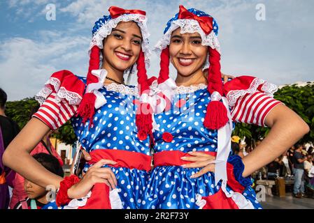 Zwei wunderschöne junge Frauen in bunten Kostümen halten an Feierlichkeiten in Plaza de Armas, Trujillo, La Libertad, Peru, Südamerika Stockfoto