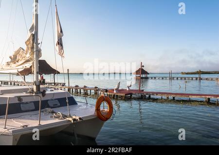 Segelboot auf dem Steg bei Sonnenaufgang über der Bacalar Lagune, Quintana Roo, Yucatan Halbinsel, Mexiko Stockfoto