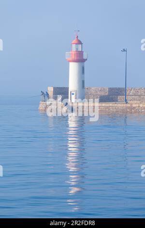 Angler am Morgen am Leuchtturm von Eruqy - Hafeneingang, bei Flut. Stockfoto