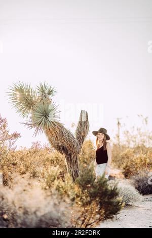 Frau steht neben Joshua Tree im Joshua Tree National Park, Joshua Tree, Los Angeles, Kalifornien, USA, Nordamerika Stockfoto