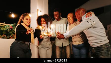 Fröhliche afrikanische Familie feiert mit einem Feuerwerk auf der Hausparty - Eltern- und Urlaubskonzept Stockfoto