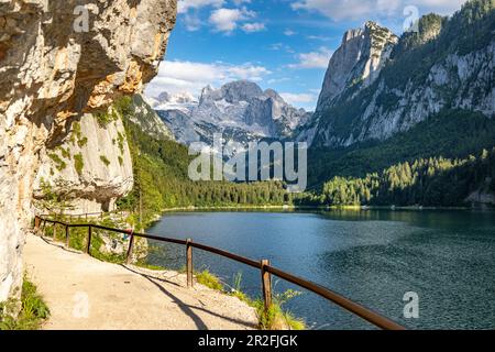 Großer Gosau-See mit Kletterwänden und einem Pfad im Vordergrund. Blick auf das Dachsteinmassiv, Salzkammergut, Oberösterreich. Stockfoto