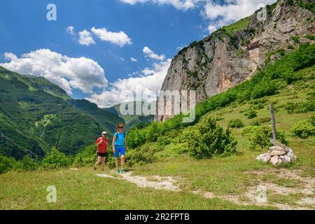 Mann und Frau wandern unter Felswand, Grande Anello dei Sibillini, Sibillini Berge, Monti Sibillini, Nationalpark Monti Sibillini, Parco nazional Stockfoto