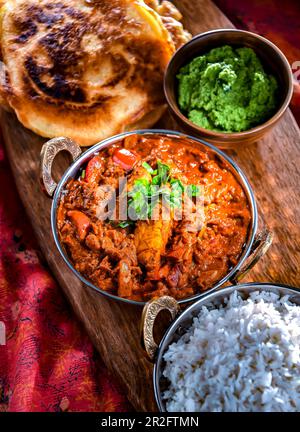 Butterhähnchen mit Reis und Naan-Fladenbrot, serviert in originalen indischen Karahi-Töpfen Stockfoto