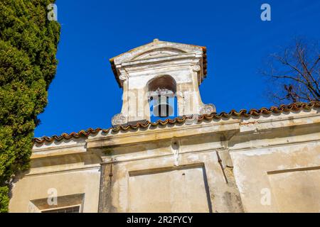 Kirche mit Glocke und einem Baum mit klarem blauen Himmel im Park San Michele in Castagnola in Lugano, Tessin in der Schweiz Stockfoto