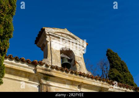 Kirche mit Glocke und einem Baum mit klarem blauen Himmel im Park San Michele in Castagnola in Lugano, Tessin in der Schweiz Stockfoto