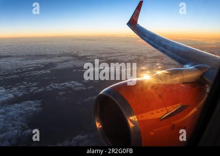 Blick vom Flugzeugfenster bei Sonnenaufgang, Flugzeugflügel Stockfoto