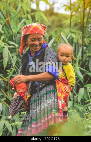 Mu cang Chai, Vietnam-27. August 2018: Smling Hmong-Stammesfrau, die ihr Kind im Rucksack in Mu cang Chai im Norden Vietnams trägt Stockfoto