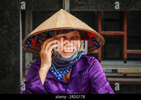 Eine vietnamesische Frau, die auf der Straße in Hanoi, Vietnam, ein Moblietelefon nimmt Stockfoto