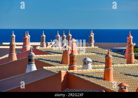 Rote Dächer mit Schornsteinen vor dem blauen Atlantik, Luz, Algarve, Portugal Stockfoto