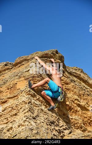 Männlicher Kletterer klettert auf eine Felswand Stockfoto