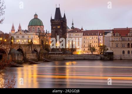 Karlsbrücke mit dem Altstädter Brückenturm, Kirche des Heiligen Kreuzes, Spuren von Licht von einem Vergnügungsboot auf der Moldau, Prag, Tschechische Republik Stockfoto