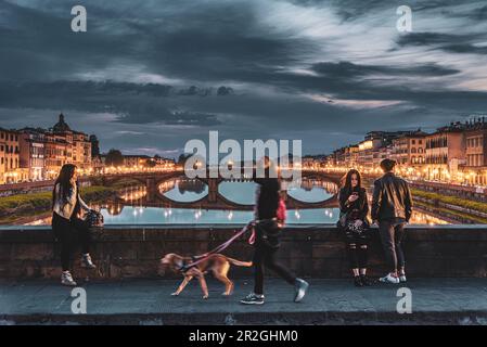 Frau mit Hund, Leute, die die Abendstimmung genießen, Brücke über Arno, Florenz, Toskana, Italien, Europa Stockfoto