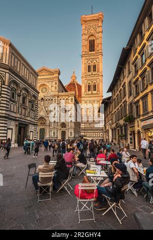 Abends gibt es Leute im Café/Restaurant vor dem Taufhaus und der Fassade des Doms, der Kathedrale Santa Maria del Fiore, Florenz, Toskana, Italien Stockfoto