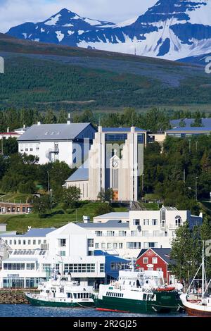 Blick über den Hafen auf die imposante Akureyrarkirkja Evangelical Lutheran Church auf einem Hügel, mit vielen Buntglasfenstern und einer großen Orgel. Stockfoto