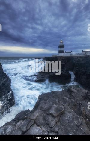 Der Leuchtturm von Loop Head auf den Klippen in stürmischer See. Nach Sonnenuntergang. Churchtown, County Wexford, Ireland.tif Stockfoto