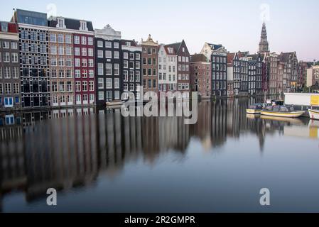 Typische Amsterdamer Häuser mit Reflexionen im Damrak-Kanal, Amsterdam, Nordholland, Niederlande Stockfoto